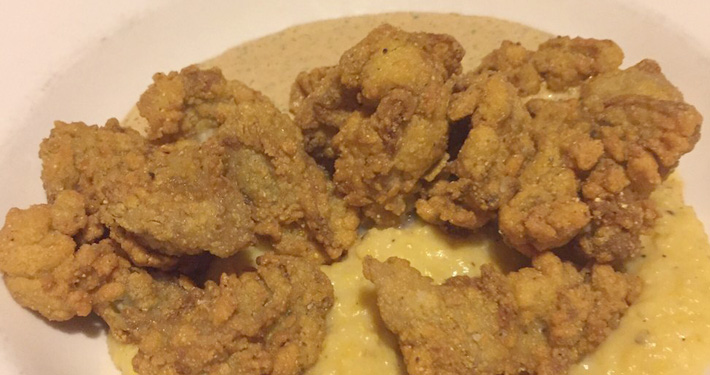 Cornmeal fried oysters piled over a bed of cheddar cheese grits.