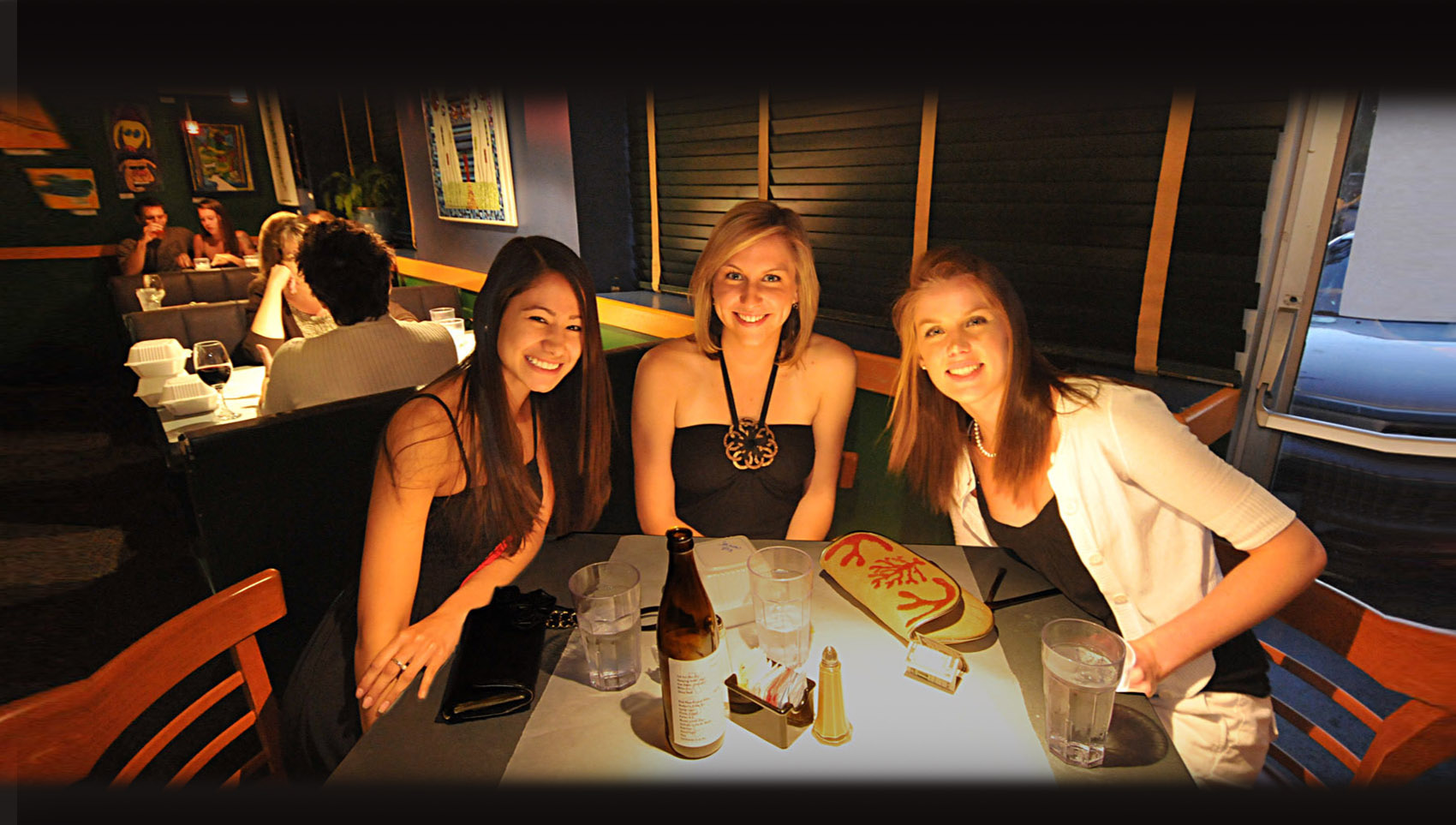 Three guests smiling at a table at Kool Beanz Cafe in the evening.