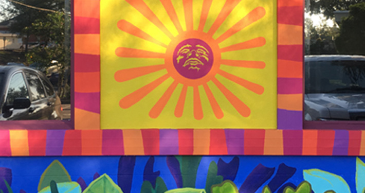 A large hand-painted mural of a stylised yellow and orange sun on the side of the building.
