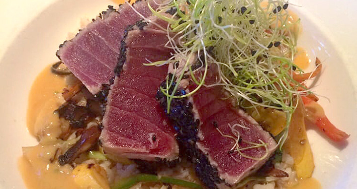Slices of rare sesame-seared tuna fanned over vegetables and topped with sprouts.