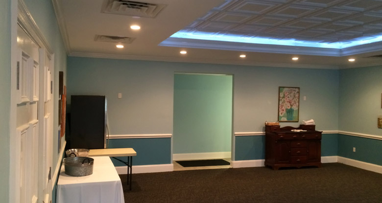 The Room at Kool Beanz, a private dining space with soft blue-grey walls, a cove-lit ceiling and framed artwork.