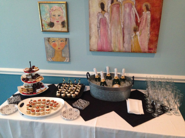 A buffet table set beneath a large painting of three figures on the wall of The Room.