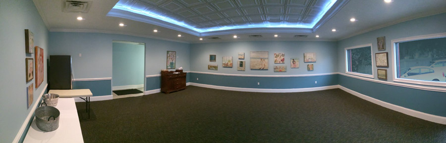 A wide view of The Room with artwork hung evenly along the walls.