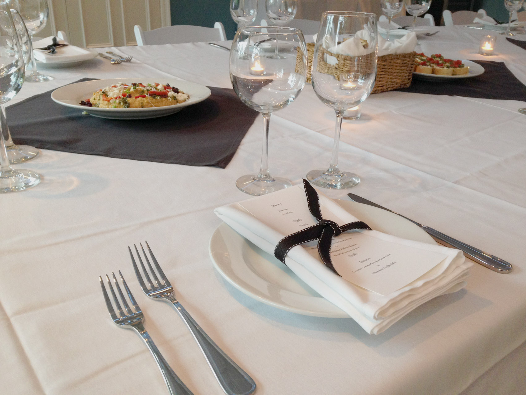 A close-up of a place setting in The Room with cutlery, a folded napkin and a wine glass.