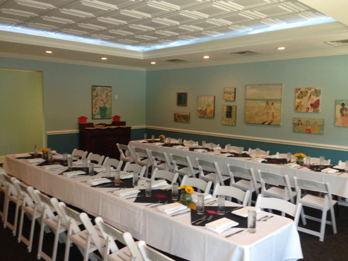The Room arranged with a single long table and white folding chairs down both sides.